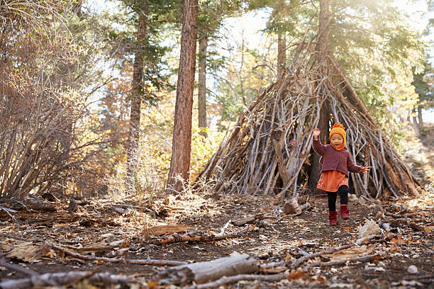istock Young girl playing outside hut made of branches in 540090196