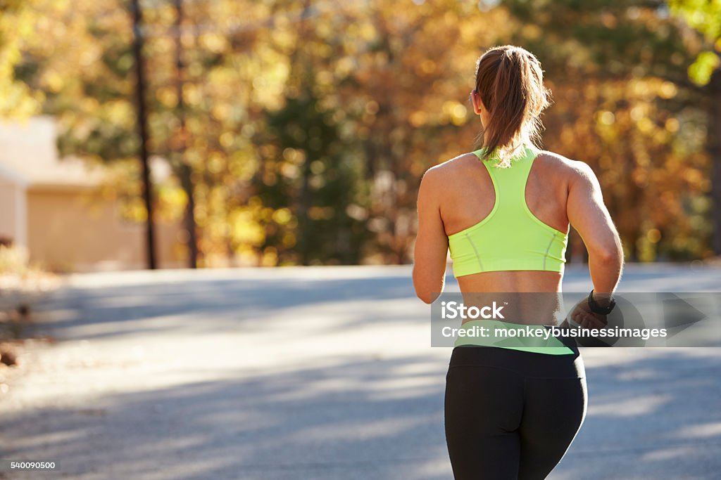 Caucasian woman jogging on country road, back view close up Women Stock Photo