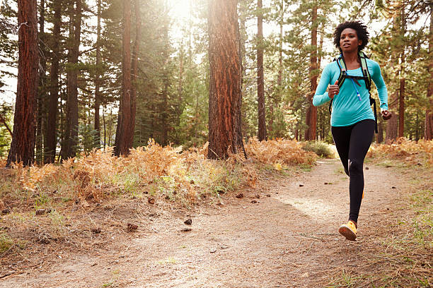 povo afro-americana mulher correndo em uma floresta - running jogging african descent nature - fotografias e filmes do acervo