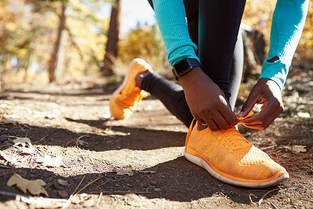 runner femminile nera in scarpa da legatura forestale, dettaglio a sezione bassa - autumn jogging outdoors running foto e immagini stock
