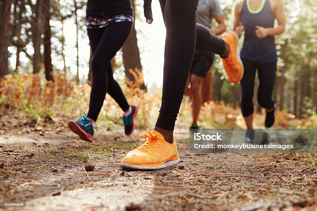 Legs and shoes of four young adults running in forest Legs and shoes of four young adults running in forest, crop Running Stock Photo