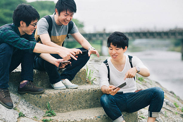 amigos a olhar para as suas mensagens no telemóvel - japanese culture asian ethnicity friendship computer imagens e fotografias de stock