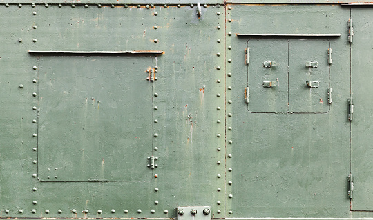 Abstract green industrial metal background texture with manholes, bolts and rivets, details of Russian armored train from WWII time