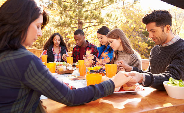 Friends at a table at a barbecue saying grace before eating Friends at a table at a barbecue saying grace before eating saying grace stock pictures, royalty-free photos & images