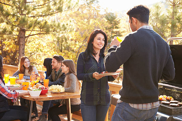 istock Friends at a table and two talking by grill at a barbecue 540095880