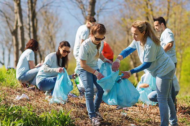 bénévoles avec sacs poubelle nettoyage parc - dépollution photos et images de collection