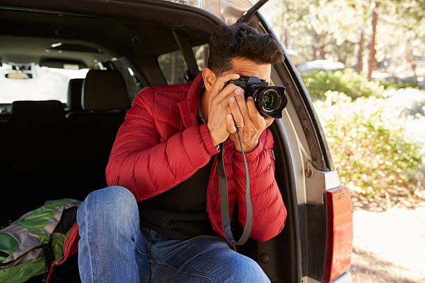istock Man sitting in the open back of car taking photos, 540096044