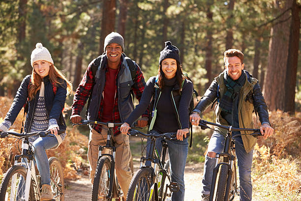 Group of four friends on bikes in a forest looking