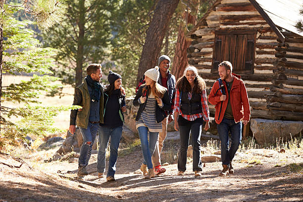 Six friends walking on forest path near a log cabin Six friends walking on forest path near a log cabin log cabin photos stock pictures, royalty-free photos & images