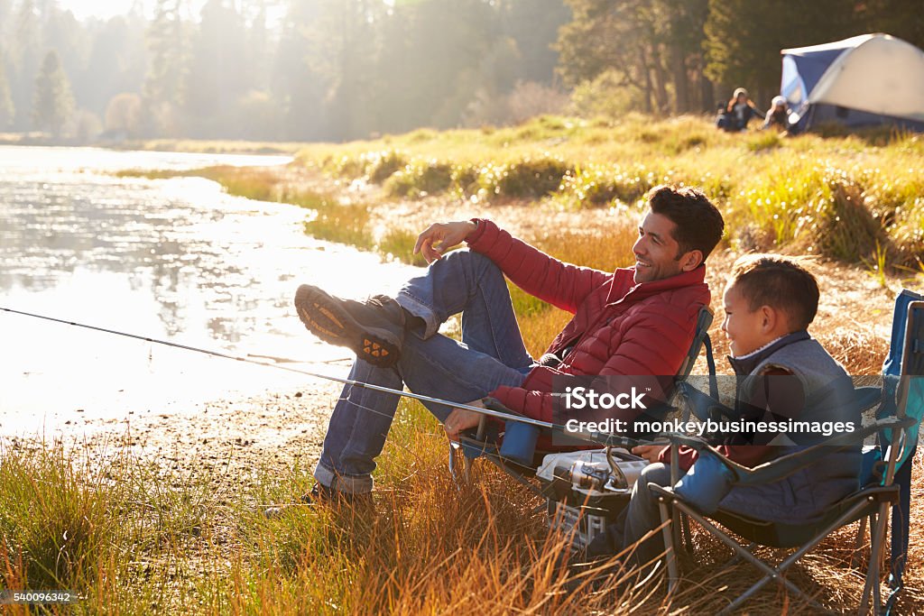 Father and son on a camping trip fishing by a lake Camping Stock Photo