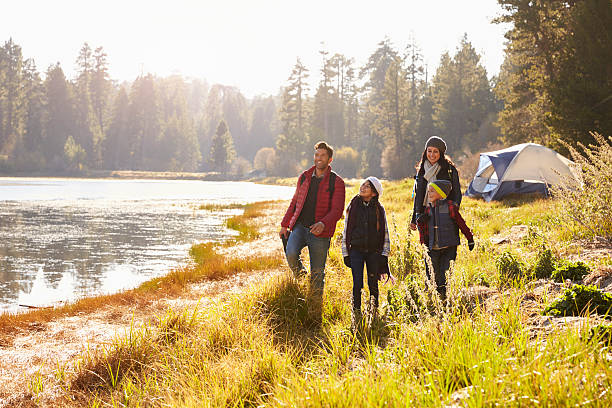 Parents and two children on camping trip walking near Parents and two children on camping trip walking near a lake camping stock pictures, royalty-free photos & images