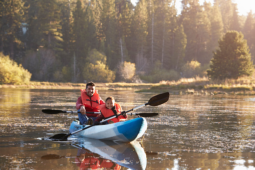 Father and son kayaking on rural lake, front view