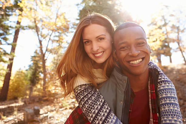 raza mixta pareja feliz abrazar durante caminar en un bosque - couple young adult african descent multi ethnic group fotografías e imágenes de stock