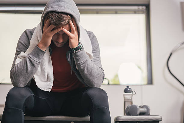 Strong sporty man breakdown Strong sporty man sitting on gym bench with towel on face, suffering breakdown to overcome. Frustration sport concept. defeat stock pictures, royalty-free photos & images