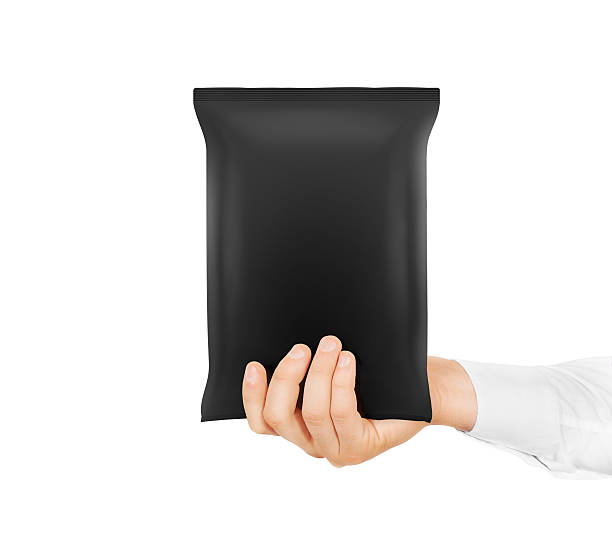 istock Blank black snack bag mock up hold in hand isolated. 540100256