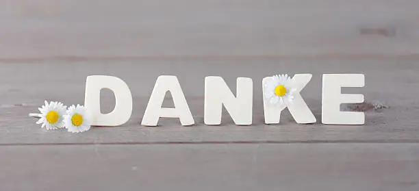 german word Danke on wodden board with daisy