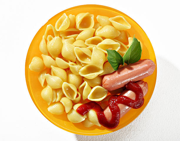 istock Expertly cooked macaroni shells with sausages in orange plate 540103046