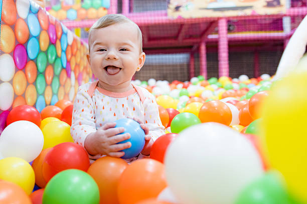美しい赤ちゃんの女の子と遊ぶカラフルなボール - playground cute baby blue ストックフォトと画像