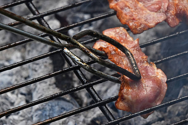 istock Tongs with bacon slice cooked on bbq grill 540106740