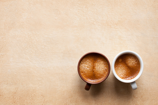 Two coffee espesso cups on brown table. Brown and white espresso cups for coffee lovers. Top view copy space for your design and text