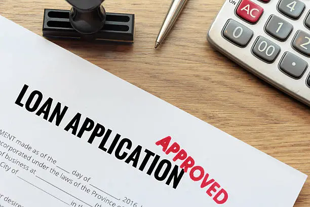Photo of Approved loan application with rubber stamp and calculator