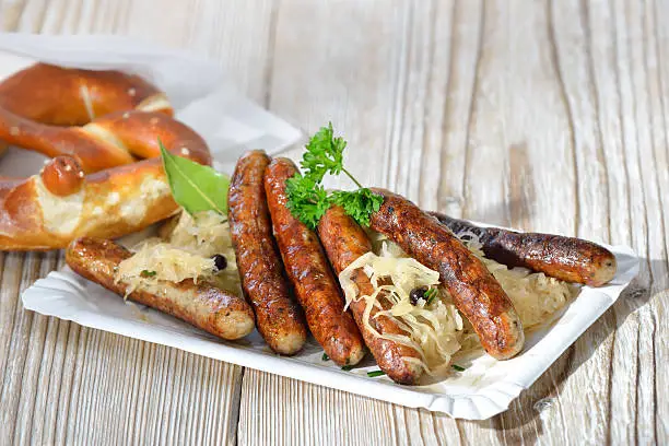 Six fried Bavarian sausages from Nuremberg served with sauerkraut and a pretzel