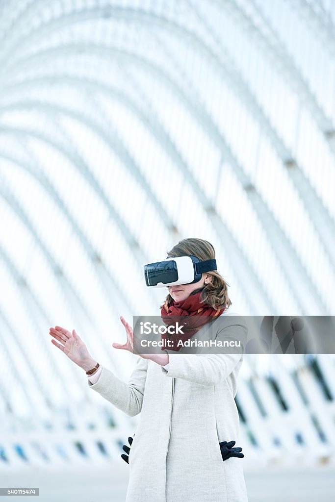 Woman wearing a virtual reality headset, controlling the experie Woman wearing a virtual reality headset, controlling the experience with hand gesture - touching and controling immaginare surfaces 30-39 Years Stock Photo