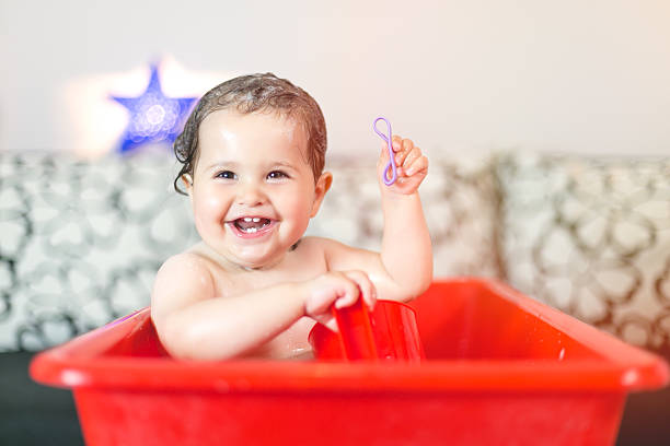 smiling and laughing while having a bath . funny and happy baby girl. showing her new teeths