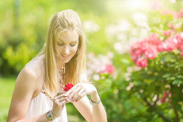 porträt von wunderschönen natürlichen junge frau festhalten roten rose - human hair women horizontal rose petals stock-fotos und bilder