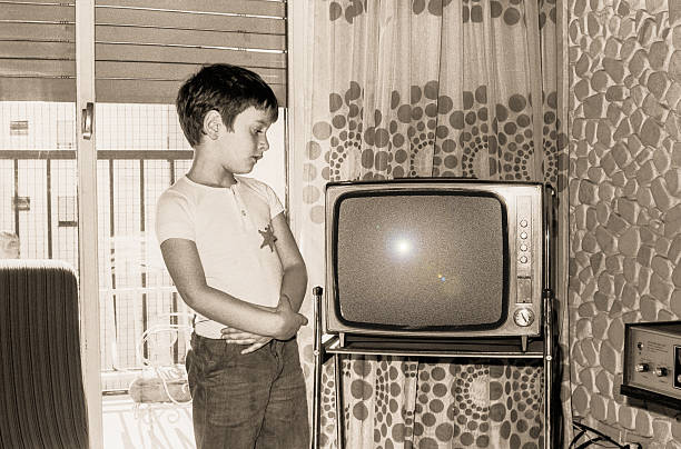 Vintage boy looking at an old tv stock photo