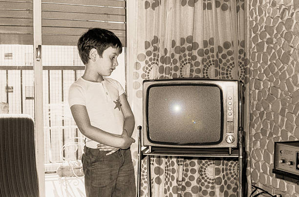 Vintage boy looking at an old tv Vintage black and white photo boy looking at an old tv old television stock pictures, royalty-free photos & images
