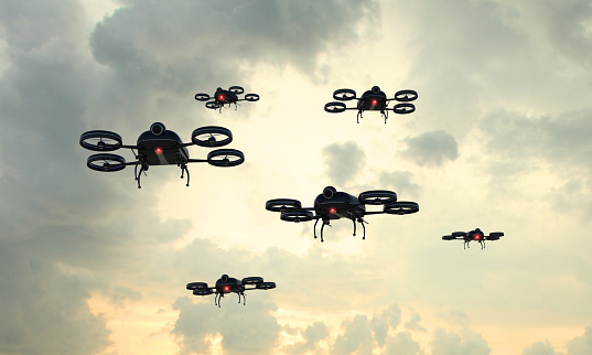 Drone invasion: fleet of remote controlled black drones flying in the sky. Rising popularity of civil drones is creating a new kind of sky traffic, with safety concerns. Composite image with digitally generated drone. 