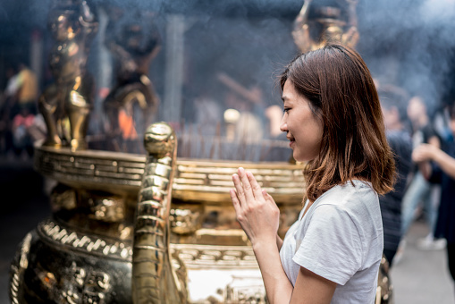 Young Asian woman praying at a Buddhist temple in Hong Kong