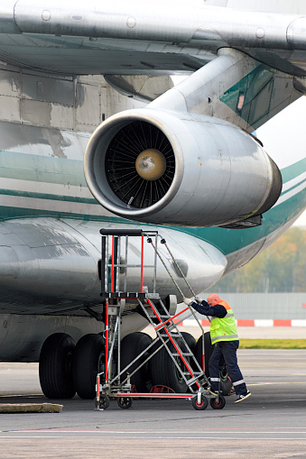 Moscow, Russia - September 26, 2014: Service Engineer serves a jet engine of the plane Il-76TD. Cargo airplane IL-76TD Alrosa airlines parked Domodedovo airport.