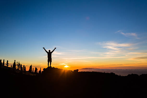 Man hiker silhouette with arms outstretched enjoy mountains stock photo