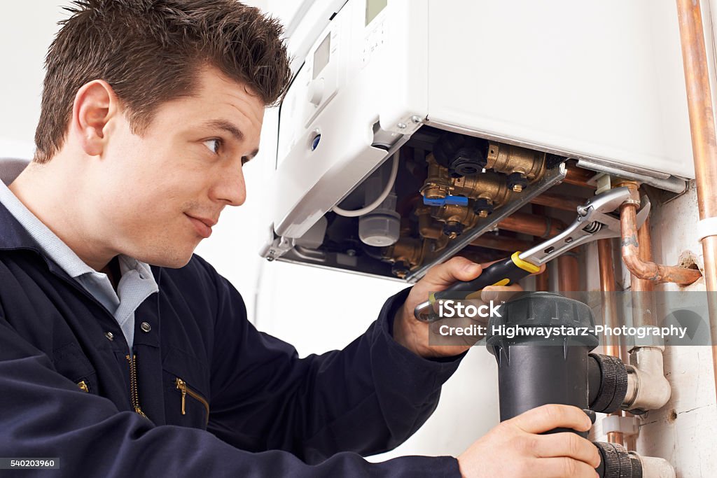 Male Plumber Working On Central Heating Boiler Plumber Stock Photo