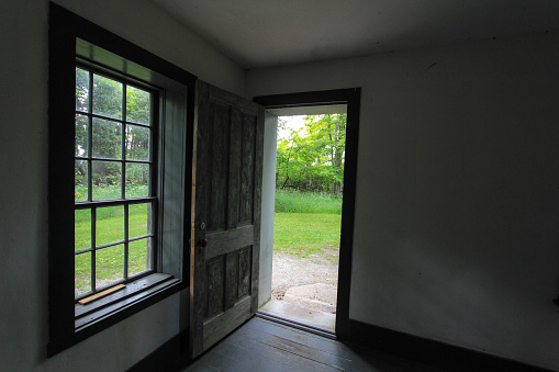 Empty room and window with open door leading outside. This is a historical building in a state park and not a privately owned residence.