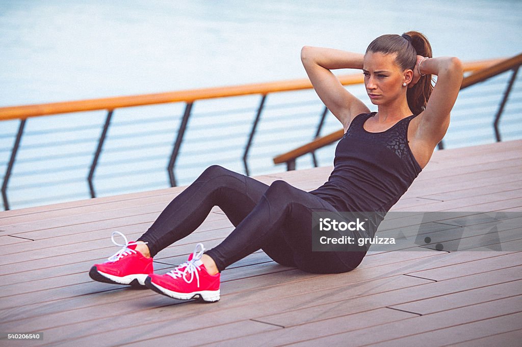 Young female athlete performs ab crunches outdoors Young female athlete performs ab crunches outdoors. Exercising Stock Photo