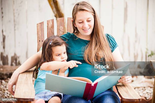 Pregnant Woman Reading To Daugther In Backyard Stock Photo - Download Image Now - Rural Scene, Healthcare And Medicine, Pregnant