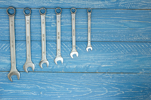 Set of wrenches hanging on a wooden board in workshop