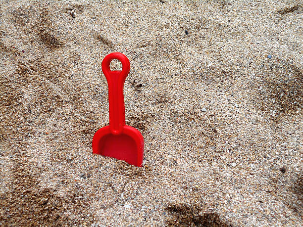 rojo pala de juguete en la playa - lost beach fotografías e imágenes de stock