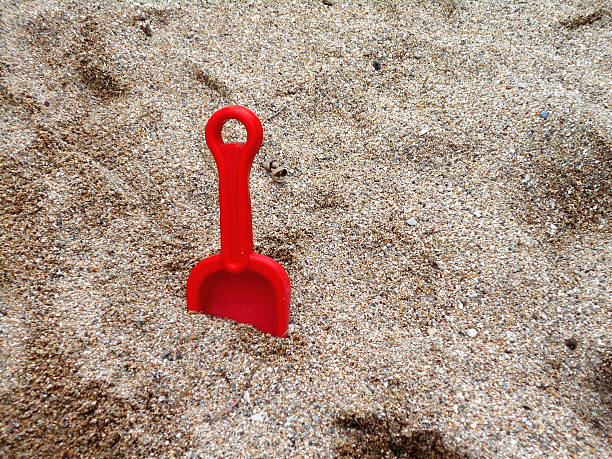 Red toy shovel stabbed into the sand