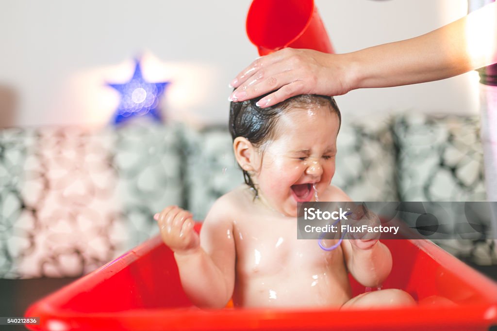 mother washing baby's hair  - pouring water cute healthy baby girl is having a bath. Baby Bathtub Stock Photo