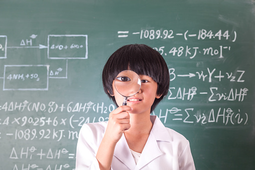 asian girl standing in front of chalk board with complicated formula and calculation studio shot