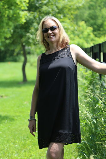 Smiling Woman Wearing Sunglasses and Black Dress