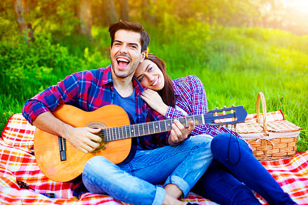 istock Couple having a picnic in the meadows, playing guitar 540220298