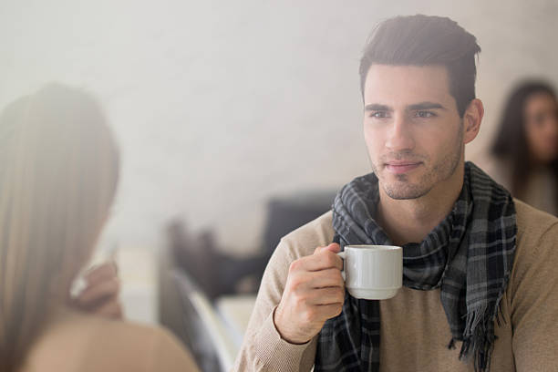 Beautiful young couple over white isolated background drinking a cup of coffee happy with big smile doing ok sign, thumb up with fingers, excellent sign
