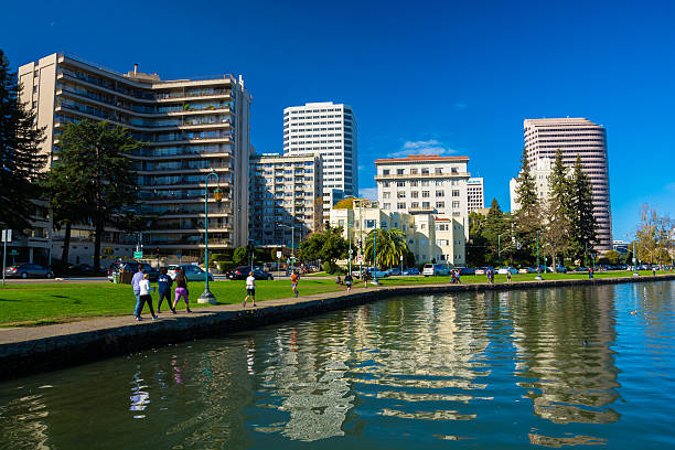 Oakland, United States - November 15, 2014: Women and men walking and jogging along the Downtown Oakland waterfront with Lake Merritt in the foreground.