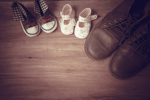 istock Daddy's boots and baby's sneakers, on wood background, fathers d 540233378