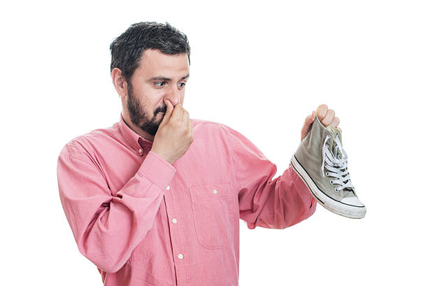 мужчина держит грязный вонючий обуви. неприятный запах вонь - human nose smelling scented unpleasant smell стоковые фото и изображения